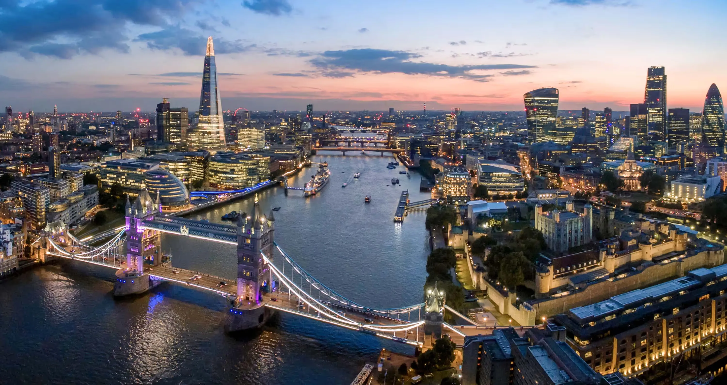 London at dusk from above, Tower Bridge and the Thames curving past the Shard and the City